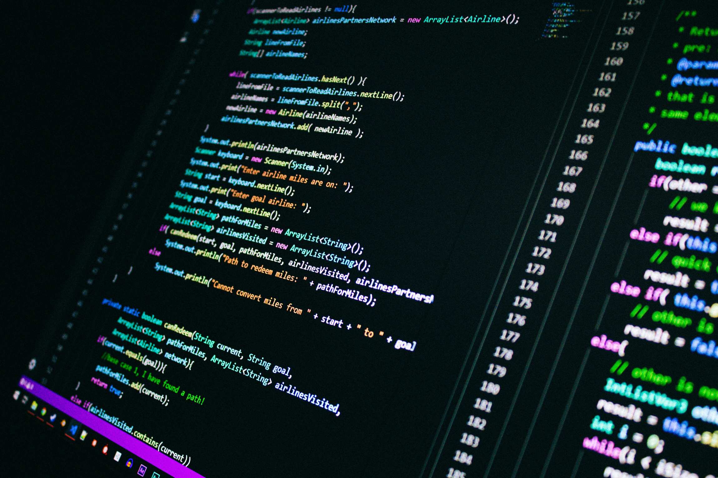 Laptop showing source code on a desk with colorful programming code on a computer screen